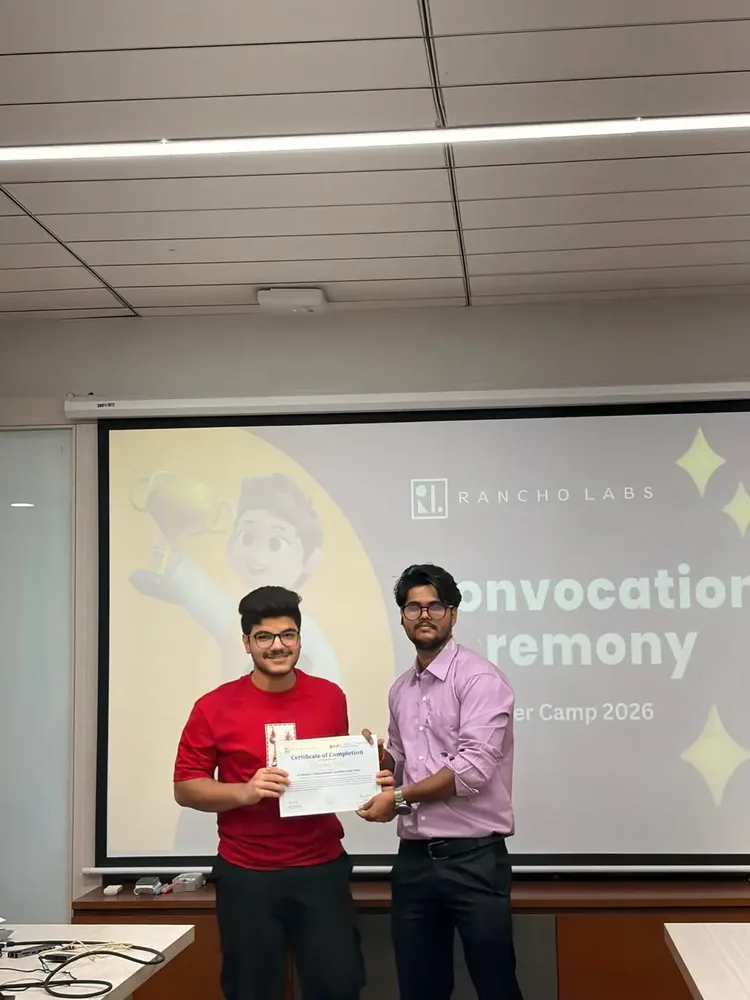 Student holding a completion certificate beside a mentor at a convocation