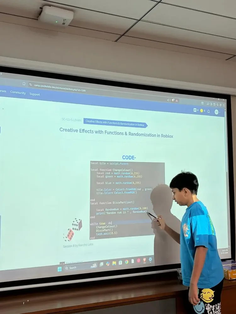 Student pointing to projected game code during a session walkthrough